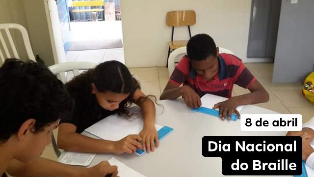 Três crianças atendidas pela ADEVIC lendo Braille, em sala de aula na ADEVIC